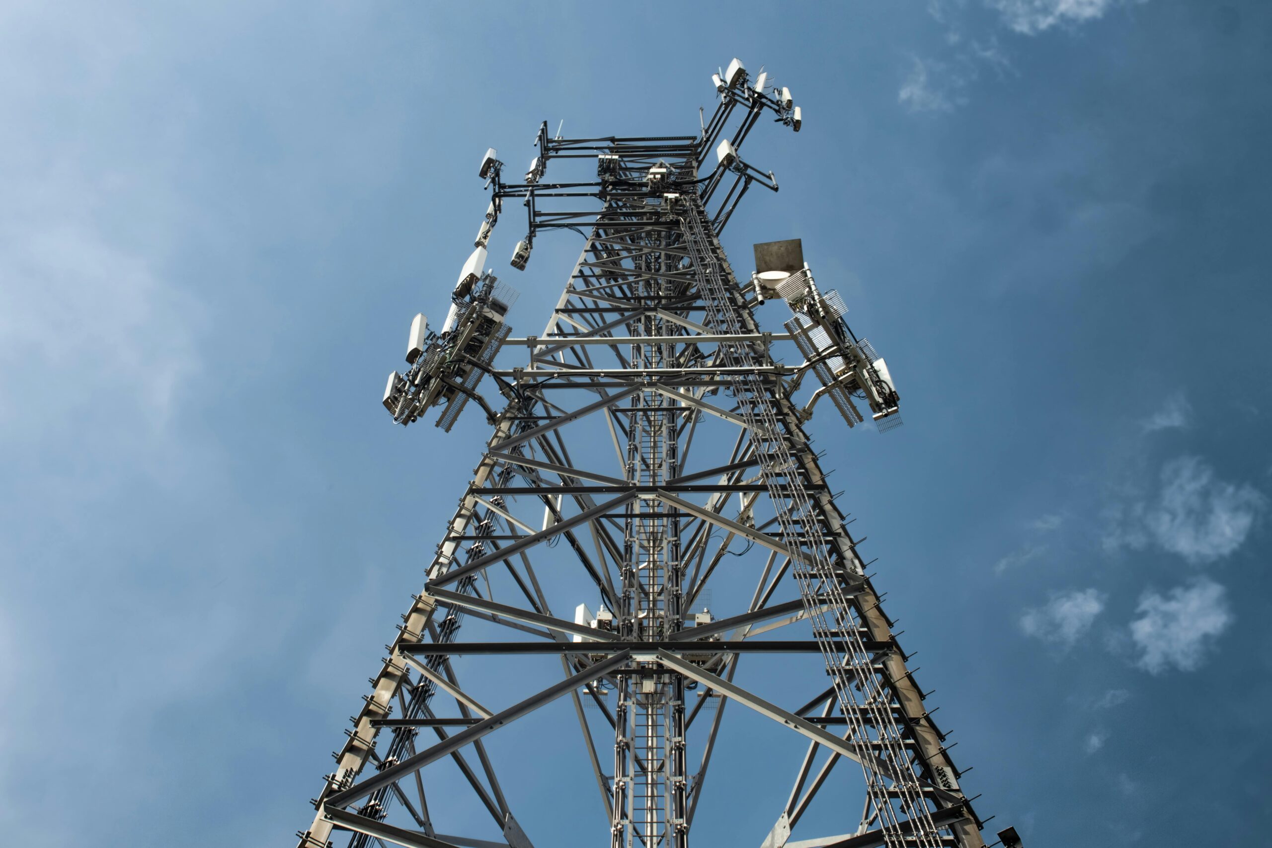 A low-angle shot of a tall metal communications tower with multiple antennas against a clear sky.